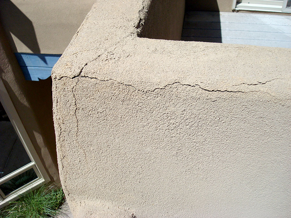 Parapet in need of repairs due to cracked stucco along corners