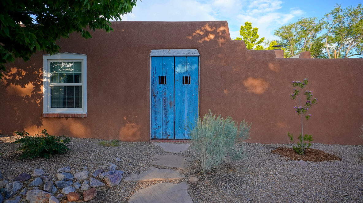 Antique blue courtyard gate leading into a pueblo style home in Albuquerque New Mexico. The home just had it's stucco repaired.