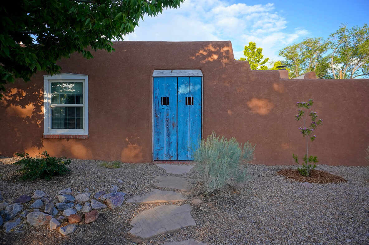 Antique blue courtyard gate leading into a pueblo style home in Albuquerque New Mexico. The home just had it's stucco repaired.