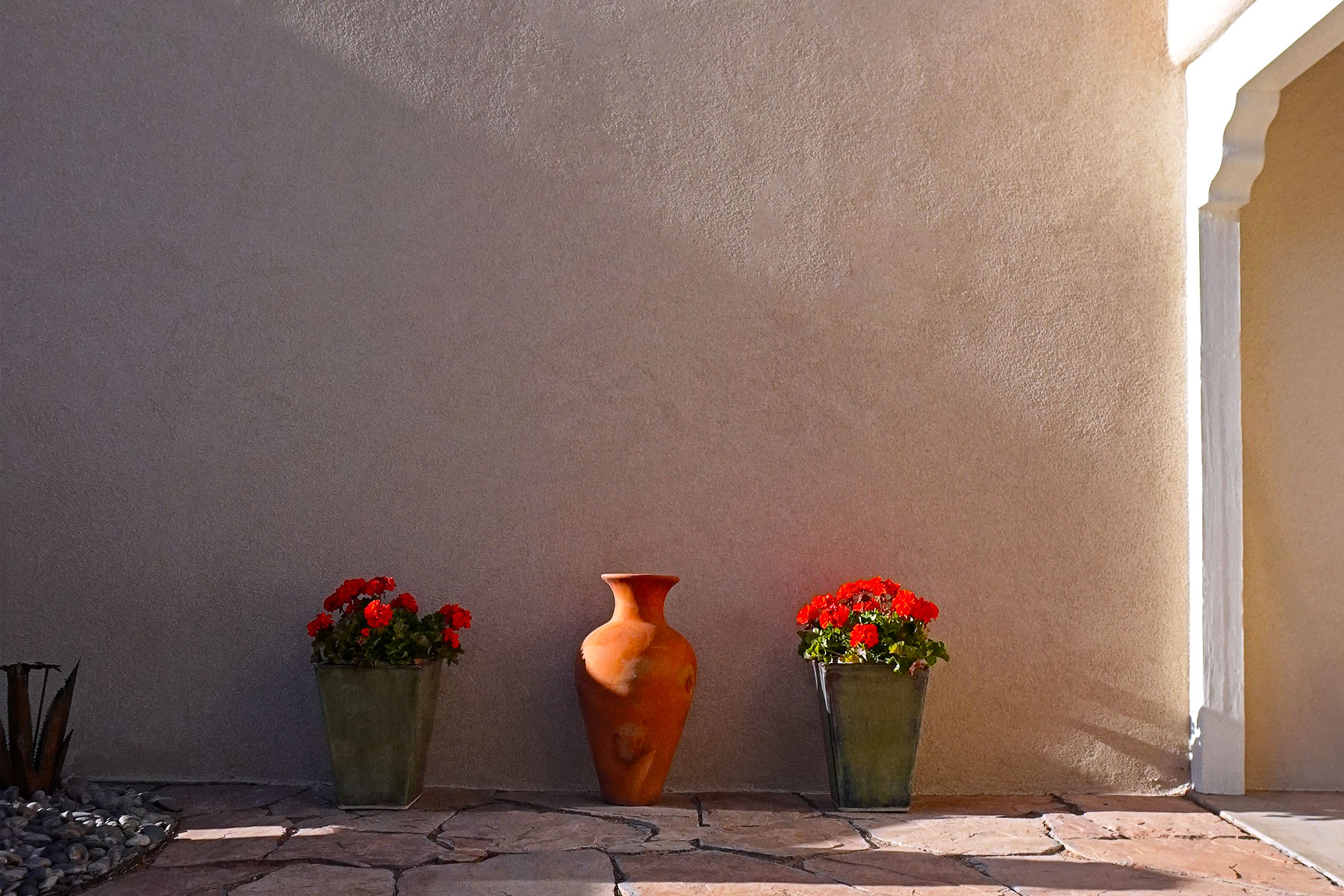 A warm sunny courtyard with three flower pots in the Albuquerque North Valley. The stucco was recently repaired and redone