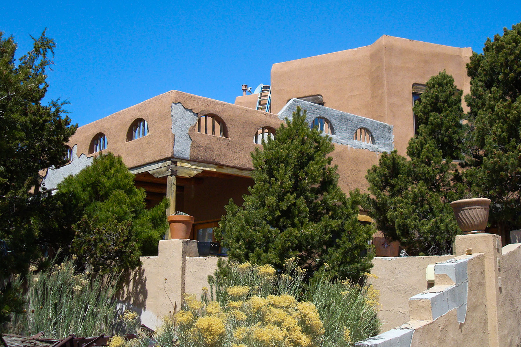 A traditional flat-roofed home in Albuquerque New Mexico with lots of stucco problems, including cracks, and stucco falling off of the walls