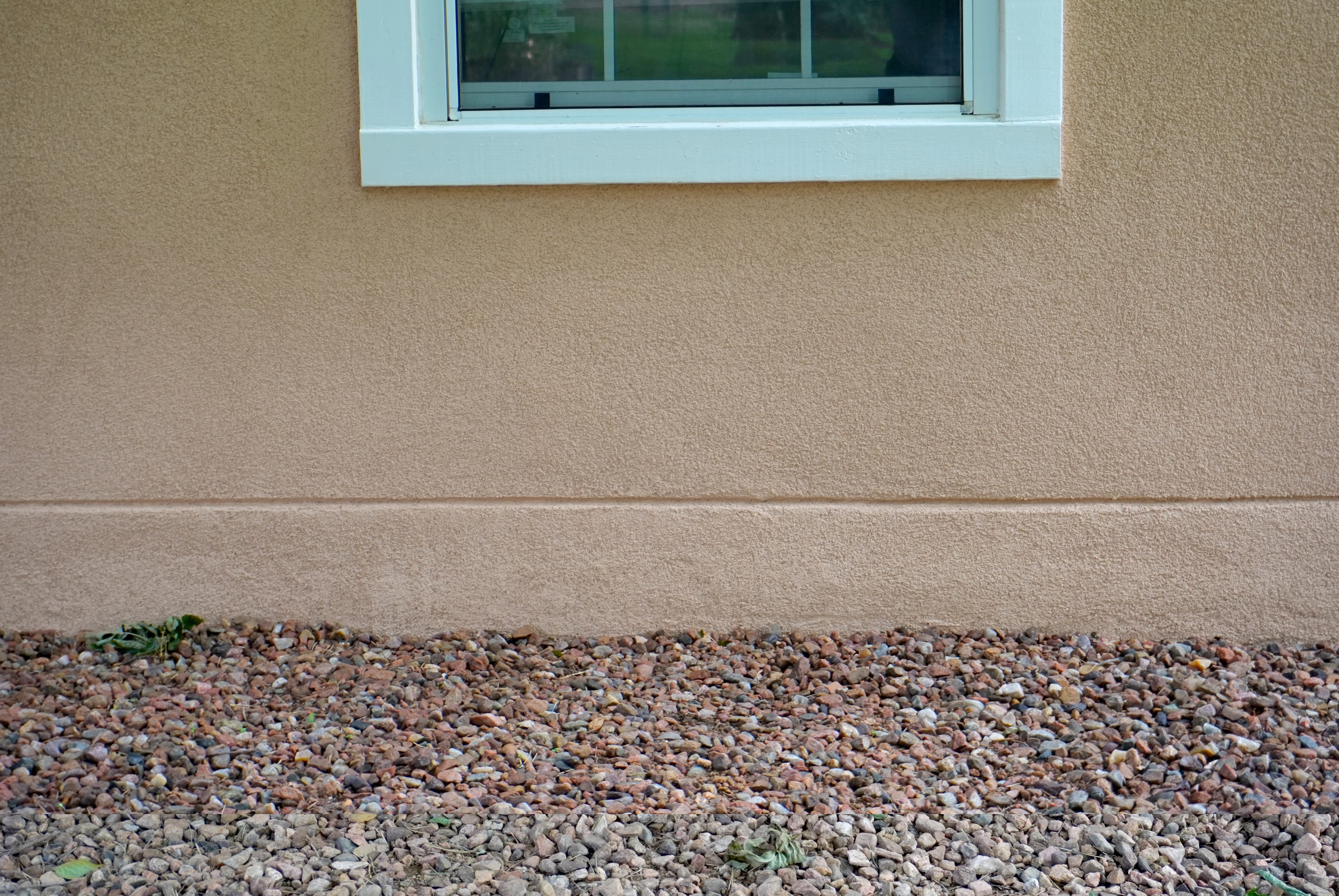 Freshly restuccoed wall under a white windowframe.