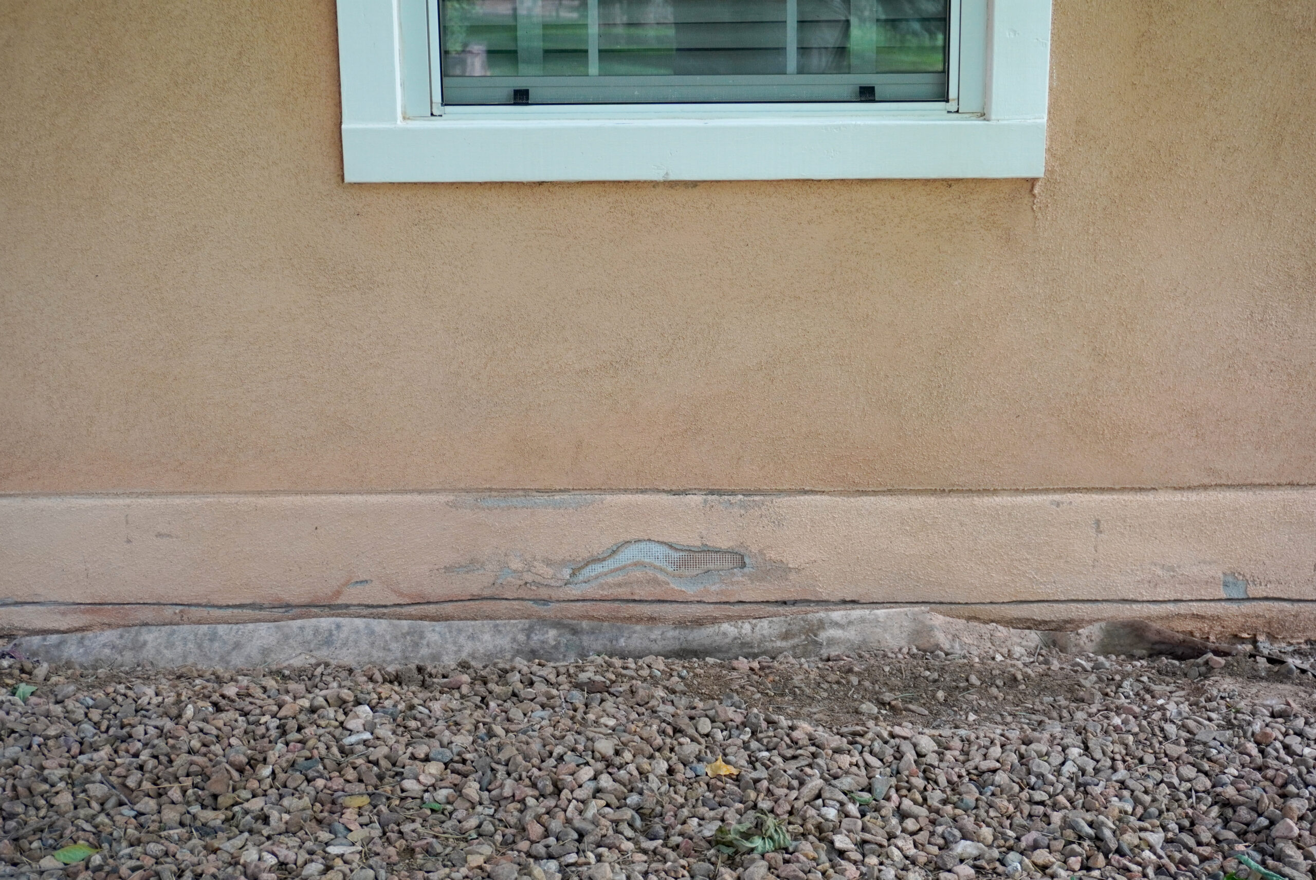 Damaged stucco wall under a window
